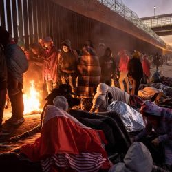 Inmigrantes se calientan junto a una hoguera al amanecer tras pasar la noche a la intemperie junto a la valla fronteriza entre Estados Unidos y México en El Paso, Texas. | Foto:John Moore/Getty Images/AFP
