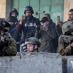 Soldados israelíes, flanqueados por periodistas, se cubren tras barreras de hormigón en medio de enfrentamientos con jóvenes palestinos tras una protesta por la muerte del preso palestino Nasser Abu Hamed en una prisión israelí en el centro de la ciudad de Hebrón, en la Cisjordania ocupada. | Foto:HAZEM BADER / AFP