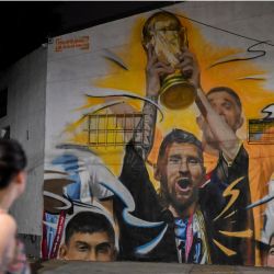 Un mural del artista Maxi Bagnasco que representa al capitán y delantero de Argentina Lionel Messi levantando el Trofeo de la Copa Mundial de la FIFA junto a sus compañeros de equipo después de ganar el torneo de la Copa Mundial Qatar 2022 se ve en Buenos Aires. | Foto:LUIS ROBAYO / AFP