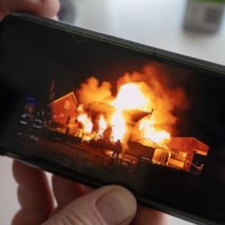 Henri Seepers shows a photograph of his former home on fire following the arson attack.