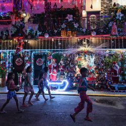 En esta foto unos niños pasan por delante de una casa con temática navideña en Manila, Filipinas. | Foto:JAM STA ROSA / AFP