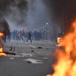 Manifestantes detrás de las llamas durante los enfrentamientos tras una manifestación de miembros de la comunidad kurda, un día después de que un hombre armado abriera fuego contra un centro cultural kurdo matando a tres personas, en la Place de la Republique de París. | Foto:JULIEN DE ROSA / AFP