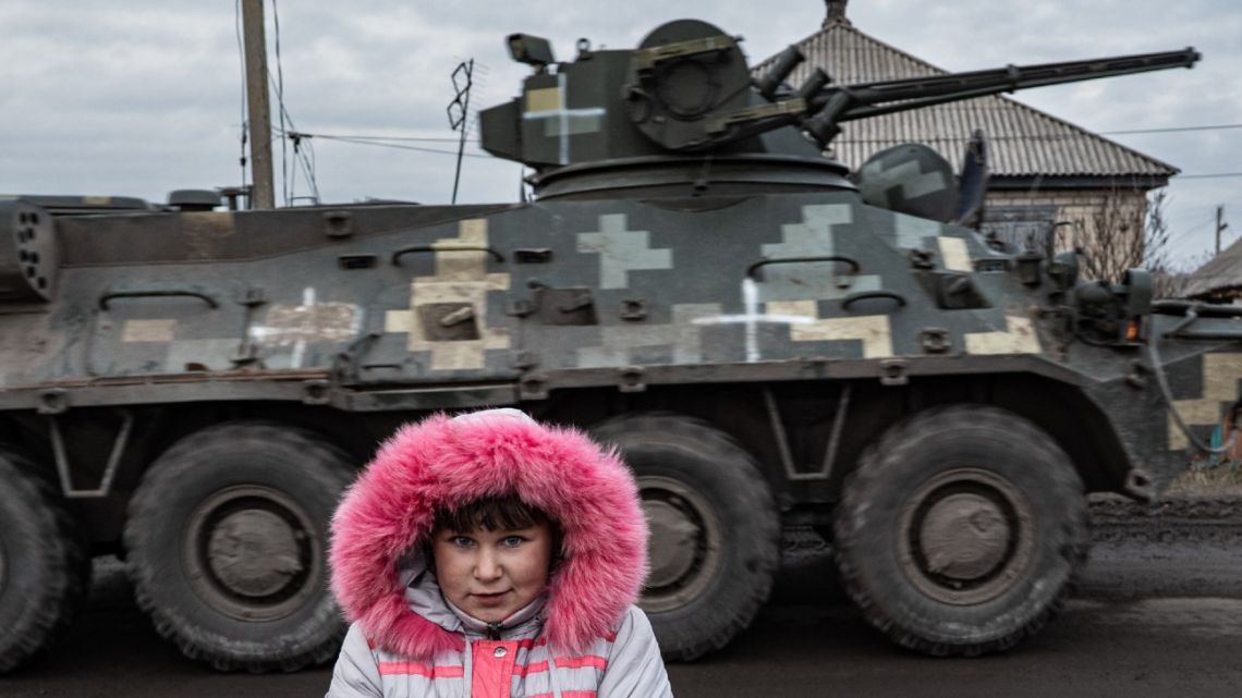 Lisa Shtanko, eight-year-old, looks on as a military vehicle passes behind in front of her house in the city of Lyman, eastern Ukraine on December 23, 2022. 