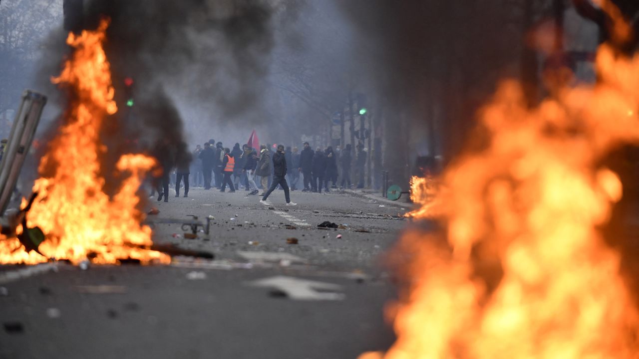 Manifestantes detrás de las llamas durante los enfrentamientos tras una manifestación de miembros de la comunidad kurda, un día después de que un hombre armado abriera fuego contra un centro cultural kurdo matando a tres personas, en la Place de la Republique de París. | Foto:JULIEN DE ROSA / AFP