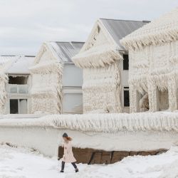 Una persona camina junto a casas cubiertas de hielo en la comunidad costera de Crystal Beach en Fort Erie, Ontario, Canadá, después de una tormenta de nieve masiva que dejó sin electricidad en la zona a miles de residentes. | Foto:COLE BURSTON / AFP