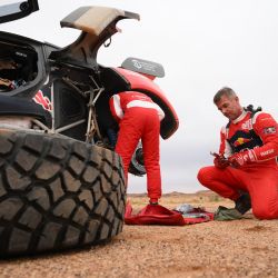 El piloto francés Sebastien Loeb y el copiloto belga Fabian Lurquin cambian neumáticos tras la cancelación de la Etapa 3 del rally Dakar 2023 entre al-Ula y Hail debido a la degradación de las condiciones meteorológicas, en Arabia Saudí. | Foto:FRANCK FIFE / AFP