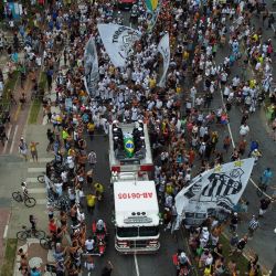 En esta imagen aérea, seguidores del fallecido astro del fútbol brasileño Pelé se reúnen en la calle mientras un camión de bomberos transporta el féretro de Pelé al Cementerio Memorial de Santos en Santos, estado de Sao Paulo, Brasil. | Foto:MIGUEL SCHINCARIOL / AFP