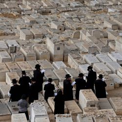 Judíos ultraortodoxos rezan sobre tumbas en el cementerio judío del Monte de los Olivos, en el este de Jerusalén. | Foto:HMAD GHARABLI / AFP