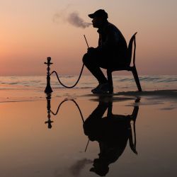 Un palestino fuma shisha en la playa en la ciudad de Gaza. | Foto:MOHAMMED ABED / AFP