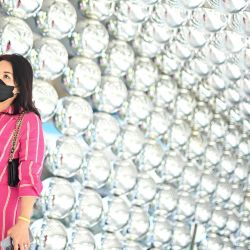 Una mujer pasa junto a una decoración hecha de bolas reflectantes en el exterior de un centro comercial en Bangkok, Tailandia. | Foto:MANAN VATSYAYANA / AFP