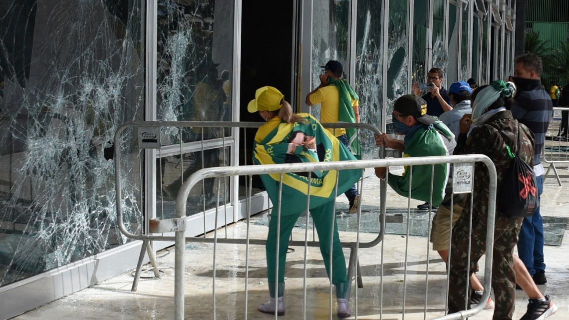 Supporters of Brazilian former President Jair Bolsonaro destroy a window of the the plenary of the Supreme Court in Brasilia on January 8, 2023.