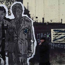Un hombre pasa junto a un mural realizado por el artista callejero griego Same84 que conmemora la deportación de los judíos de Tesalónica, la segunda ciudad de Grecia, a los campos nazis de Auschwitz-Birkenau que habían sido pintados con esvásticas y símbolos fascistas, en Tesalónica. Foto de Sakis MITROLIDIS / AFP | Foto:AFP
