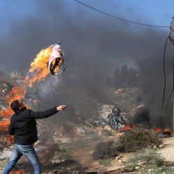 Un manifestante palestino intenta arrojar un neumático en llamas a través de la controvertida barrera de separación de Israel durante una manifestación cerca de la aldea de Qalandia. Foto de AHMAD GHARABLI / AFP | Foto:AFP