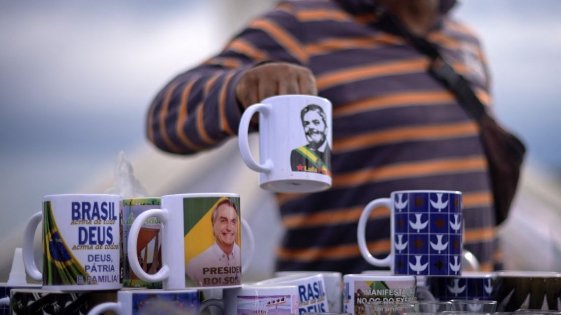 A vendor shows a mug depicting Brazilian President Luiz Inacio Lula da Silva next to another with the image of former president Jair Bolsonaro in front of the Cathedral of Brasilia in Brasilia on January 21, 2023. 