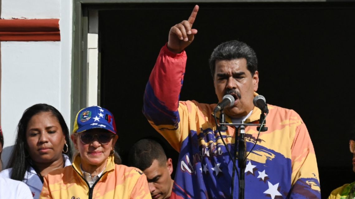Venezuelan President Nicolás Maduro, next to his wife Cilia Flores, addresses supporters from a balcony at the Miraflores Palace, during a rally to commemorate the 65th anniversary of the 1958 Popular Insurrection, in Caracas on January 23, 2023. 