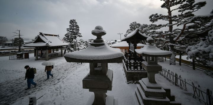 Un grupo de personas visita el templo Zenkoji de Nagano, cubierto de nieve, en Japón.