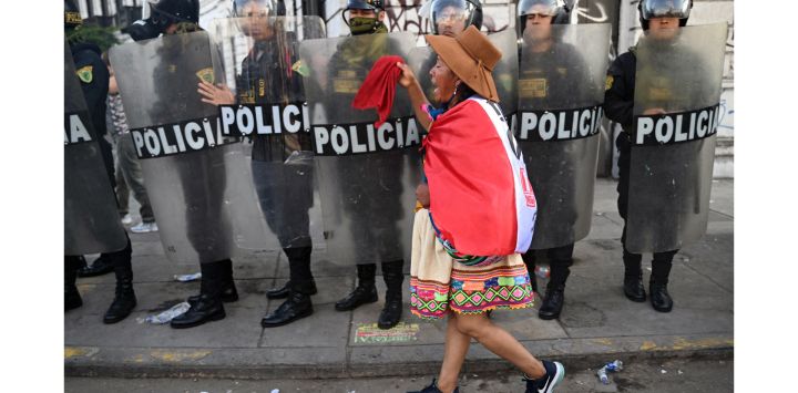 Una mujer indígena camina frente a la policía antidisturbios durante una protesta que exige la dimisión de la presidenta de Perú, Dina Boluarte, en Lima.