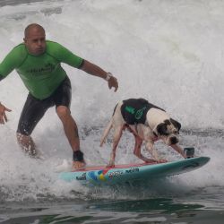 Domingo Pianezzi, acompañado de su perro "Makakilo", surfea en la playa San Bartolo, en el sur de Lima, Perú. | Foto:Xinhua/Mariana Bazo