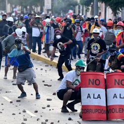 Manifestantes lanzan piedras a la policía antidisturbios durante enfrentamientos dentro de una protesta contra el gobierno de Dina Boluarte pidiendo su renuncia y el cierre del Congreso, en Lima, Perú. | Foto:ERNESTO BENAVIDES / AFP