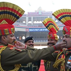 Soldados indios de la Fuerza de Seguridad Fronteriza posan mientras se ofrecen caramelos unos a otros durante las celebraciones para conmemorar el Día de la República del país en el puesto fronterizo de Wagah entre India y Pakistán, a unos 35 km de Amritsar. | Foto:Narinder Nanu / AFP