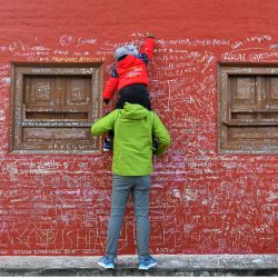 Un niño, ayudado por su padre, escribe un mensaje con tiza en un muro del templo de Saraswati con motivo del festival hindú de 'Basanta Panchami', en Katmandú, Nepal. | Foto:PRAKASH MATHEMA / AFP