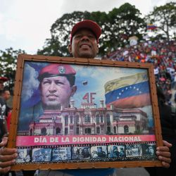 Un partidario del presidente de Venezuela, Nicolás Maduro, sostiene una imagen del fallecido presidente venezolano Hugo Chávez y asiste a una concentración para conmemorar el 65 aniversario de la Insurrección Popular de 1958 a lo largo de la céntrica avenida Sucre, en Caracas. | Foto:Federico Parra / AFP