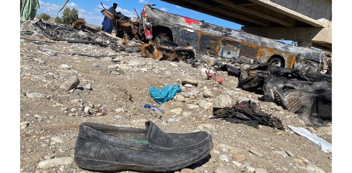 Un residente observa los restos de un autobús de pasajeros incendiado en Bela, en el distrito de Lasbela, en la provincia paquistaní de Baluchistán. - Al menos 40 personas murieron cuando un autobús se precipitó por un puente en el suroeste de Pakistán y estalló en llamas, dijo un funcionario del gobierno.