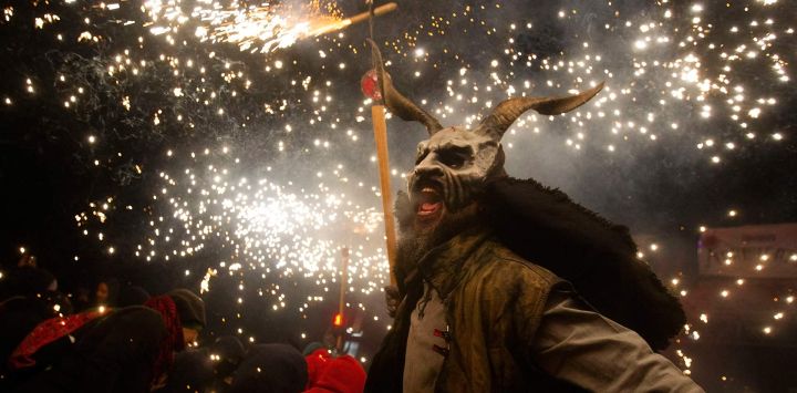 Un participante con una máscara de demonio blande un palo con fuegos artificiales entre los juerguistas durante la tradicional fiesta del Correfoc en Palma de Mallorca.