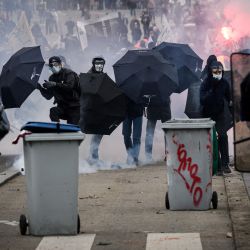 Policías antidisturbios franceses se paran frente a personas con paraguas mientras se producen enfrentamientos durante una manifestación en un segundo día de huelgas y protestas en todo el país por la reforma de las pensiones propuesta por el gobierno, en Nantes. | Foto:LOIC VENANCE / AFP