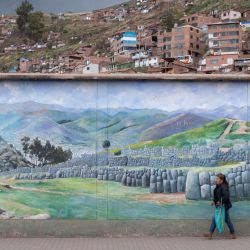 Una mujer camina junto a un mural de la fortaleza inca de Sacsahuaman en la ciudad de Cusco, Perú,, mientras el número de turistas que llegan al popular destino turístico sigue disminuyendo debido a las protestas en curso en todo el país. | Foto:CRIS BOURONCLE / AFP