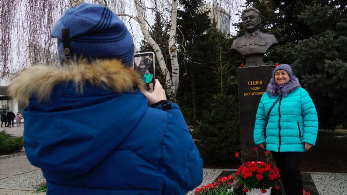 A woman poses by the newly unveiled bronze bust of Soviet leader Joseph Stalin outside the museum dedicated to the Battle of Stalingrad in the southern Russian city of Volgograd on February 1, 2023, on the eve of commemorations of the Soviet victory in the Stalingrad battle. 