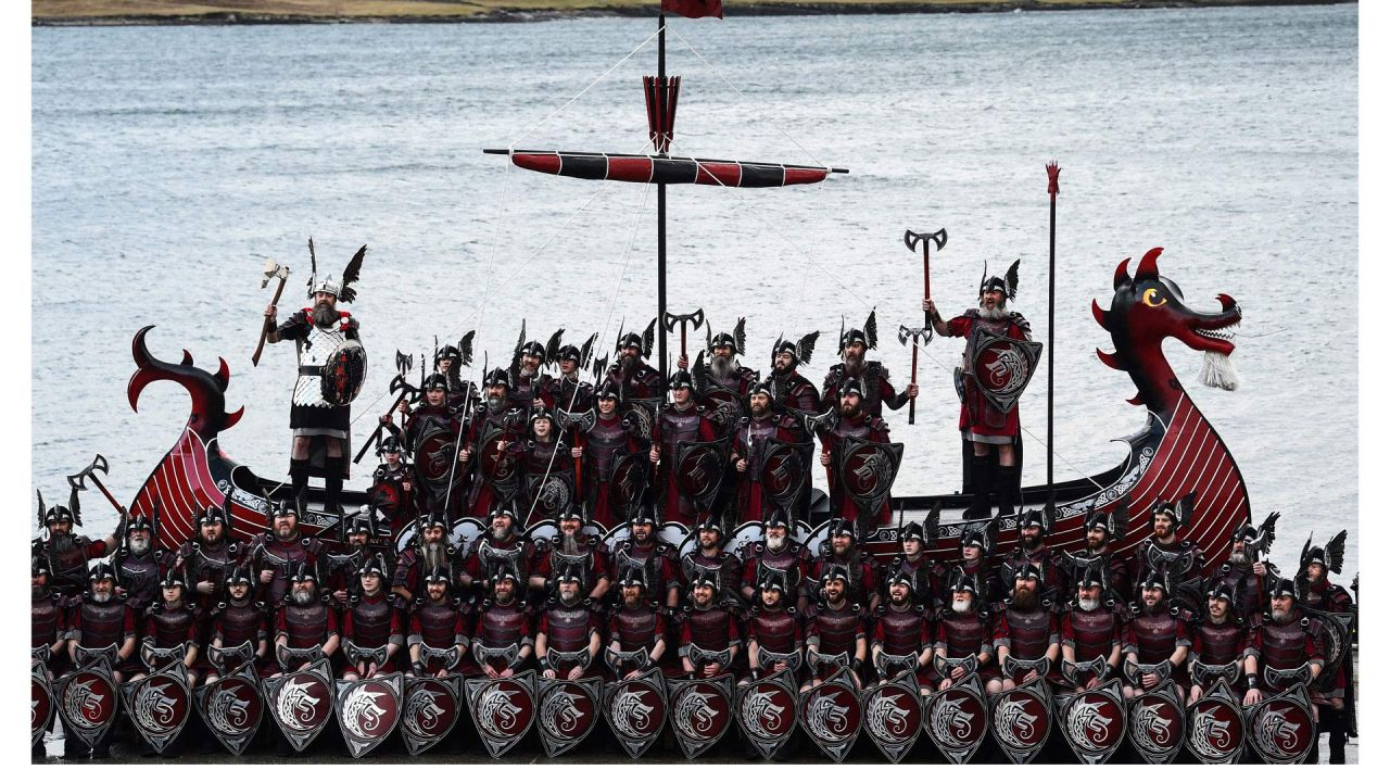 Miembros del "Escuadrón Jarl" de Up Helly Aa posan para una fotografía con su galera vikinga en Lerwick, Islas Shetland, antes del festival Up Helly Aa que se celebra ese mismo día. - Up Helly Aa celebra la influencia de los vikingos escandinavos en las islas Shetland y culmina con hasta 1.000 "guizers" (hombres disfrazados) lanzando antorchas encendidas a su lancha vikinga y prendiéndole fuego más tarde por la noche. | Foto:Andy Buchanan / AFP