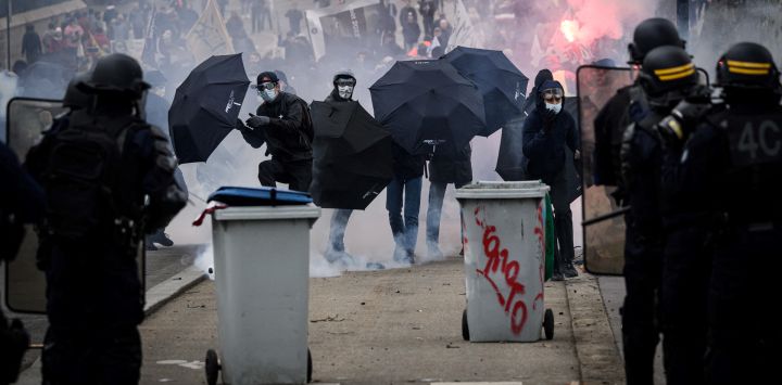 Policías antidisturbios franceses se paran frente a personas con paraguas mientras se producen enfrentamientos durante una manifestación en un segundo día de huelgas y protestas en todo el país por la reforma de las pensiones propuesta por el gobierno, en Nantes.