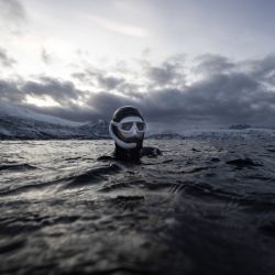 El francés Arthur Guerin-Boeri, cinco veces campeón del mundo de apnea, calienta antes de sumergirse en las profundidades para avistar orcas, en la isla de Spildra, al norte del Círculo Polar Ártico. | Foto:Olivier Morin / AFP