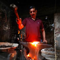 Un herrero iraquí martilla barras de hierro caliente en un taller del barrio de al-Shawakah, en el centro de Bagdad. | Foto:AHMAD AL-RUBAYE / AFP