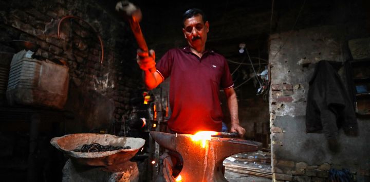 Un herrero iraquí martilla barras de hierro caliente en un taller del barrio de al-Shawakah, en el centro de Bagdad.