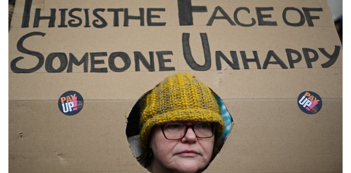Un profesor sostiene una pancarta mientras participa en una protesta organizada por NEU y otros sindicatos afiliados en la plaza de San Pedro, en Manchester.