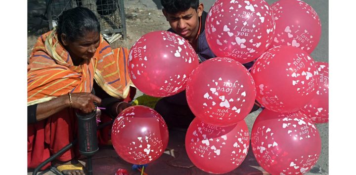 Una mujer se prepara para vender globos a los viajeros en un cruce de carreteras en Amritsar, India.