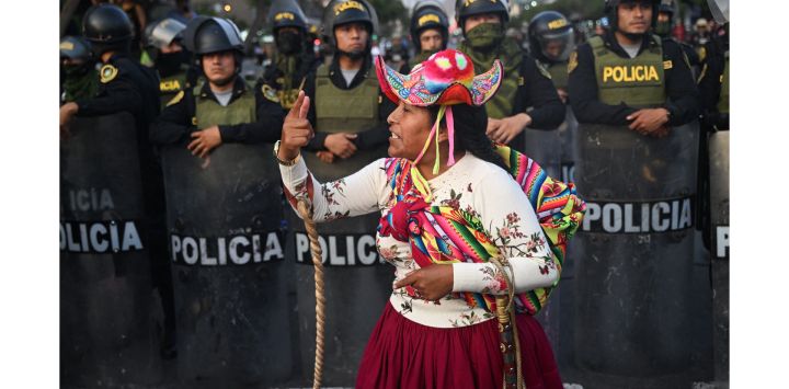 Un manifestante gesticula frente a policías durante una manifestación contra el gobierno de la presidenta peruana Dina Boluarte en Lima. - Los manifestantes que han paralizado partes de Perú durante semanas cerraron el aeropuerto internacional de Lima, mientras los legisladores consideraban adelantar las elecciones en un intento por poner fin a la mortal movilización.