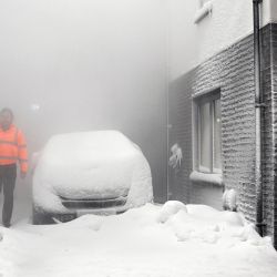 Un ingeniero camina a través de una tormenta de nieve simulada entre dos casas construidas para desarrollar futuras soluciones de calefacción en la Casa de la Energía 2.0 de la Universidad de Salford en Salford, noroeste de Inglaterra. | Foto:PAUL ELLIS / AFP