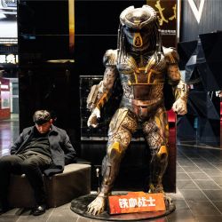 Un hombre duerme junto a una estatua a tamaño real del personaje cinematográfico Predador en un centro comercial de Pekín. | Foto:NOEL CELIS / AFP