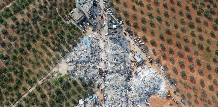 Esta vista aérea muestra a los residentes buscando víctimas y supervivientes entre los escombros de los edificios derrumbados tras un terremoto en el pueblo de Besnia, cerca del municipio de Harim, en la provincia siria de Idlib, controlada por los rebeldes y situada en la frontera con Turquía.