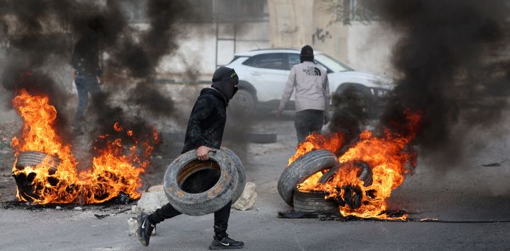 Manifestantes palestinos queman neumáticos para bloquear una carretera que conduce a Jericó, en la Cisjordania ocupada, tras una redada de las fuerzas israelíes en la ciudad.