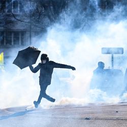 Un manifestante con un paraguas expulsa un perdigón de gas lacrimógeno durante una manifestación en el tercer día de concentraciones organizadas en todo el país desde principios de año contra una reforma de las pensiones profundamente impopular en Nantes, oeste de Francia. | Foto:LOIC VENANCE / AFP