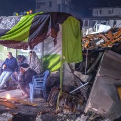 Varias personas descansan junto a una hoguera entre los escombros en Hatay, tras el terremoto de magnitud 7,8 que sacudió el sureste del país. - Un terremoto de magnitud 7,8 sacudió Turquía y Siria, matando a más de 3.000 personas y arrasando miles de edificios mientras los equipos de rescate excavaban con las manos desnudas en busca de supervivientes. | Foto:BULENT KILIC / AFP