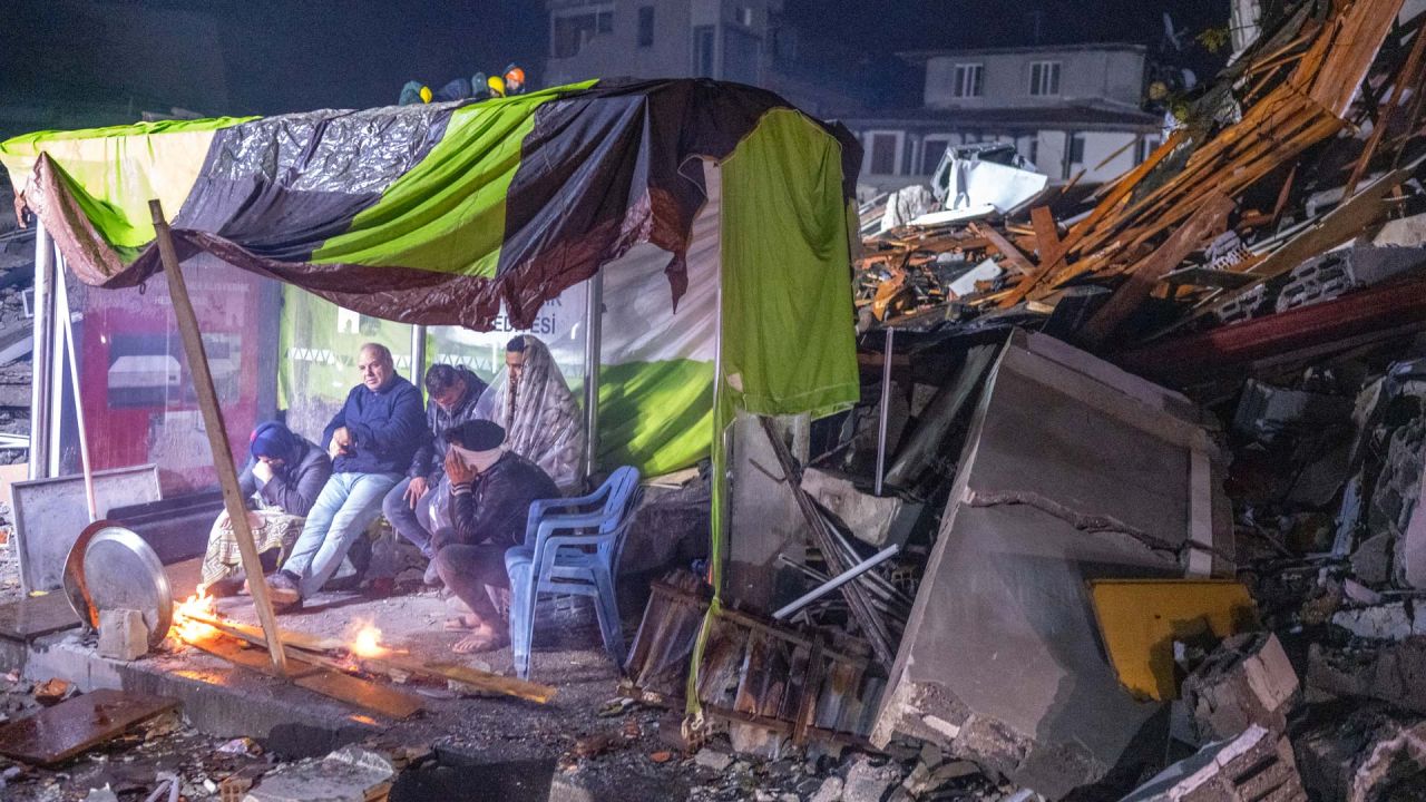 Varias personas descansan junto a una hoguera entre los escombros en Hatay, tras el terremoto de magnitud 7,8 que sacudió el sureste del país. - Un terremoto de magnitud 7,8 sacudió Turquía y Siria, matando a más de 3.000 personas y arrasando miles de edificios mientras los equipos de rescate excavaban con las manos desnudas en busca de supervivientes. | Foto:BULENT KILIC / AFP