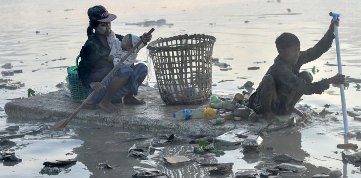 Esta foto muestra a unos recolectores de residuos remando botes de poliestireno mientras buscan plástico y vidrio para reciclar en el arroyo Pazundaung de Yangón. - Decenas de recolectores de residuos de Myanmar se lanzan a las turbias aguas de un arroyo de Yangón tras verse obligados a buscar trabajo por la crisis económica posterior al golpe de Estado.