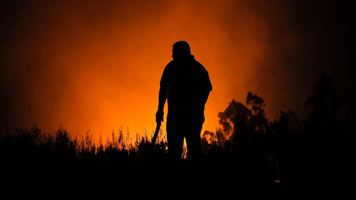 The silhouette of a person is seen against a forest fire background in Rafael, Tome Comune, Bio Bio Region, Chile, on February 8, 2023.