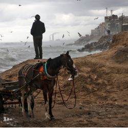 Palestinos se reúnen junto al mar Mediterráneo en la ciudad de Gaza durante una tormenta. | Foto:MAHMUD HAMS / AFP