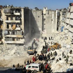 Soldados sirios observan cómo los equipos de rescate buscan víctimas y supervivientes entre los escombros de un edificio derrumbado en la ciudad septentrional de Alepo, días después de que un mortífero terremoto sacudiera Turquía y Siria. | Foto:AFP